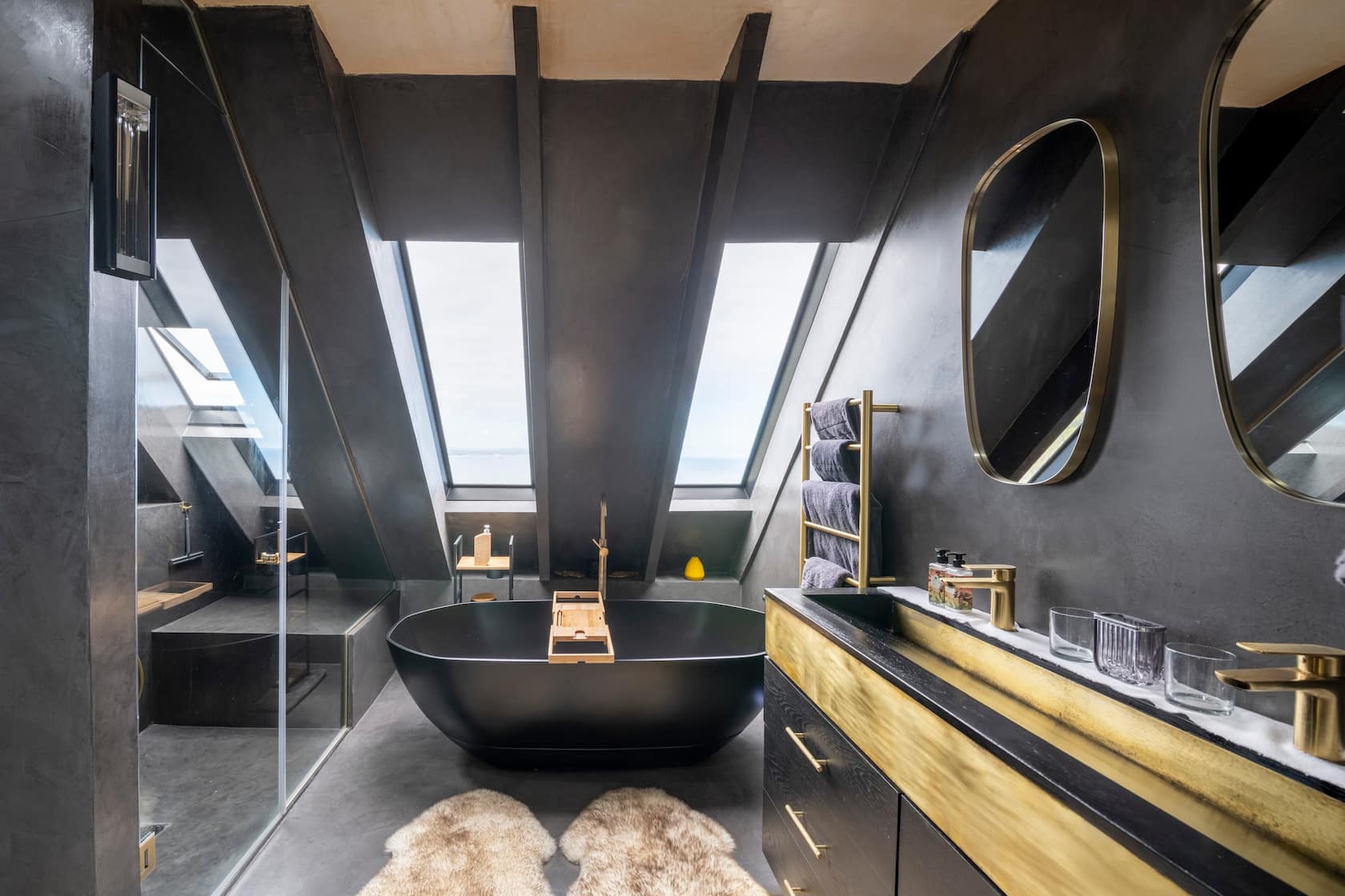 Dark en-suite with a freestanding tub beneath angled skylights