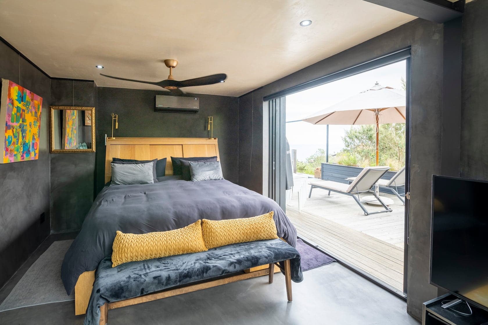 Bedroom opening to a deck with loungers and ocean beyond