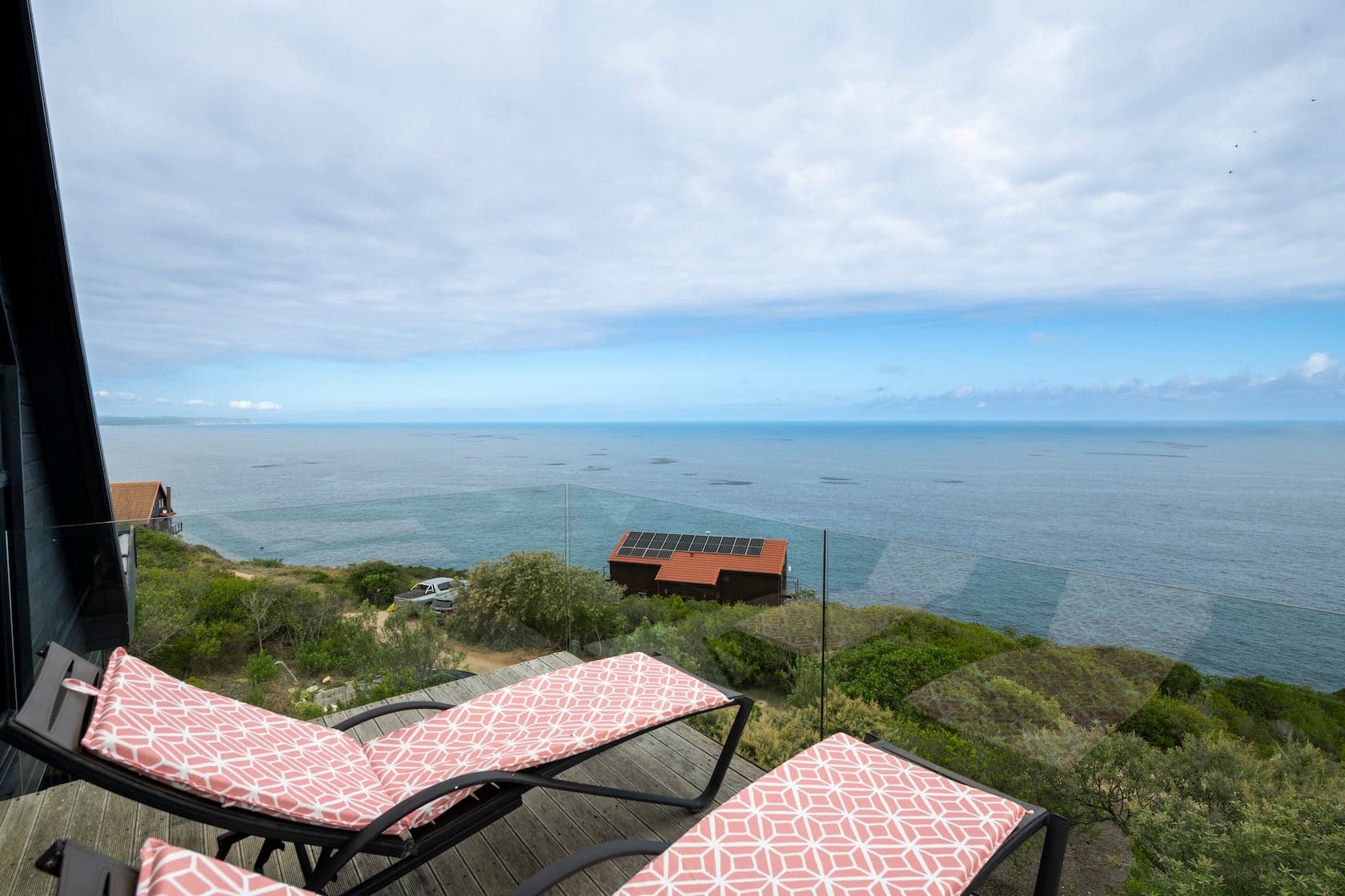 Cushioned sun loungers on the deck overlooking the ocean