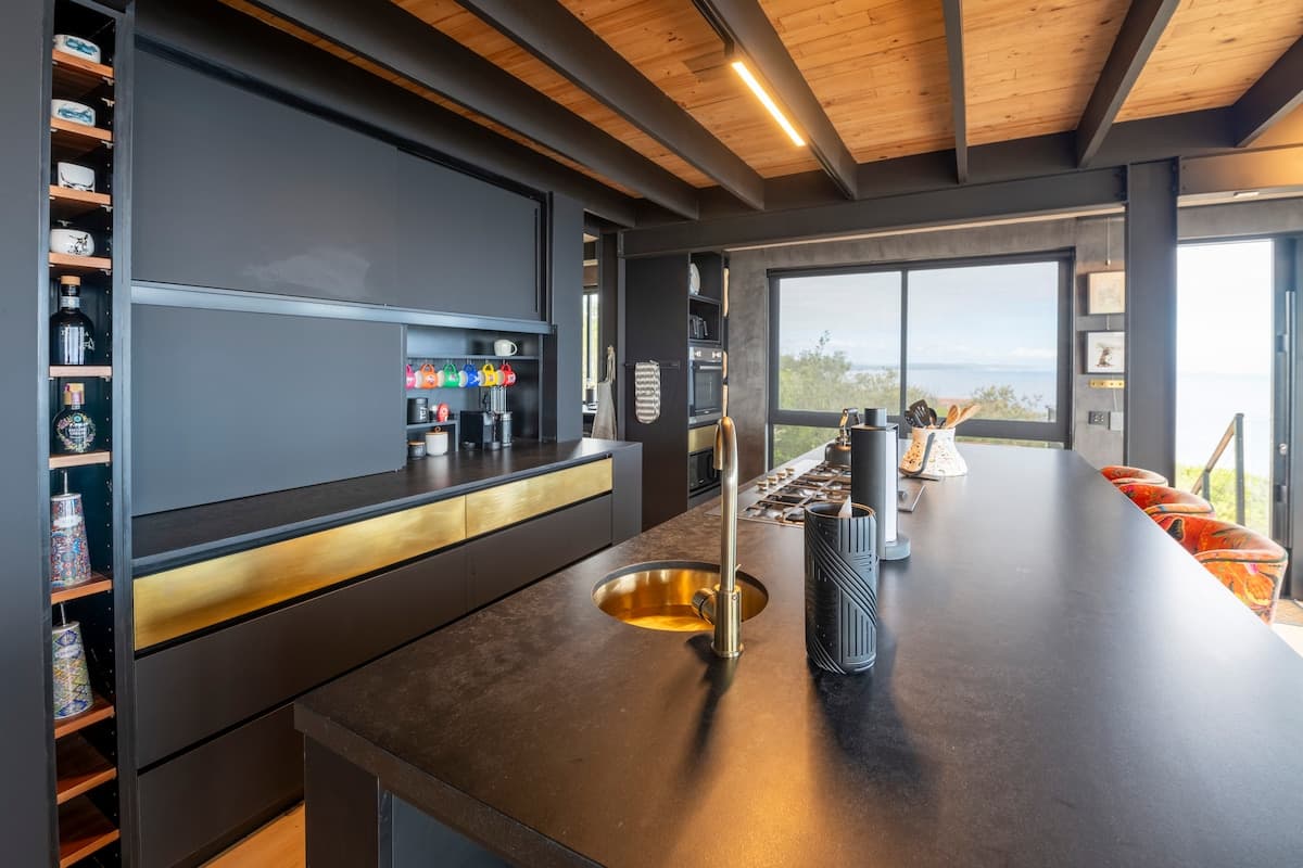 Chef's kitchen with a dark island, brass sink and ocean window